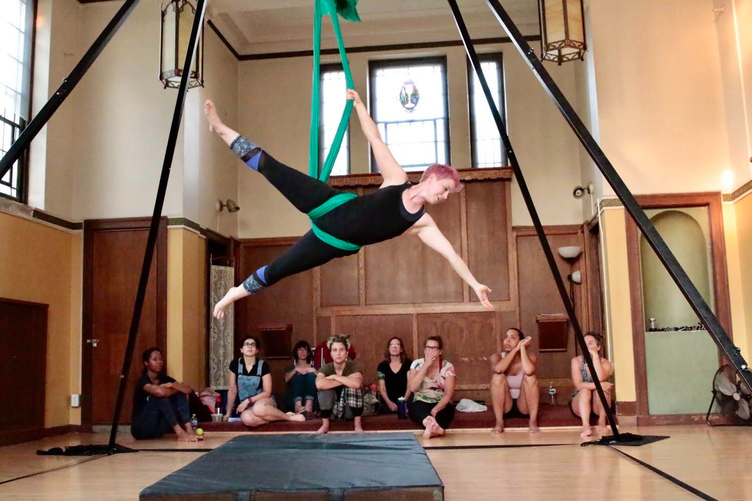 A dancer in aerial silks while a group watches