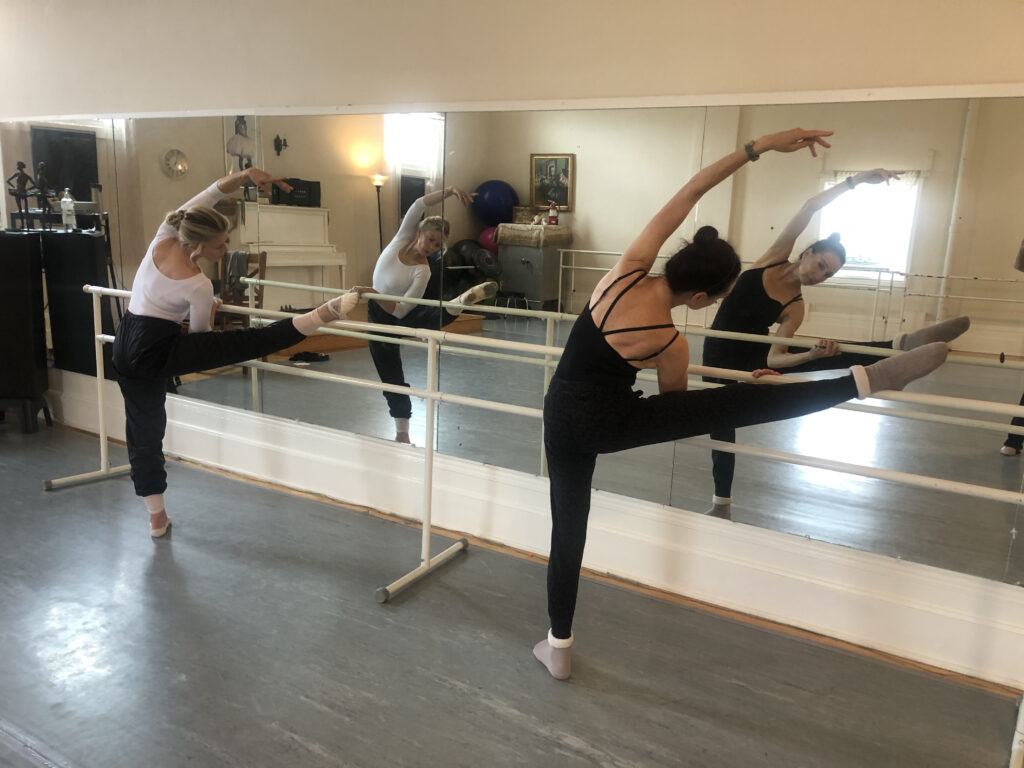 2 ballet dancers stretching at the barre