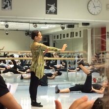 Person with arms extended forward in the center, with people on the floor with legs in the air 